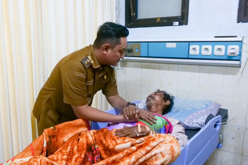 Wakil Bupati Lumajang Yudha Adji Kusuma menggenggam tangan salah satu pedagang korban robohnya lapak Pasar Krai saat menjenguk di ruang perawatan RSUD dr. Haryoto Lumajang, Selasa (20/1/2026).