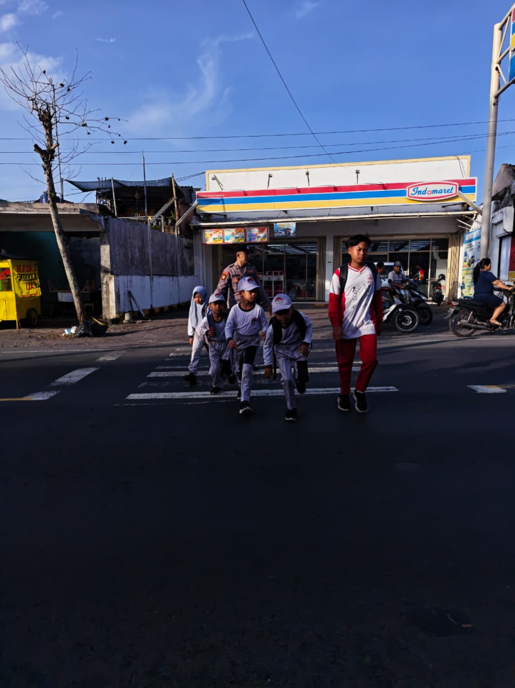 Polisi Polsek Pasirian membantu siswa menyeberang jalan demi keselamatan saat jam masuk sekolah