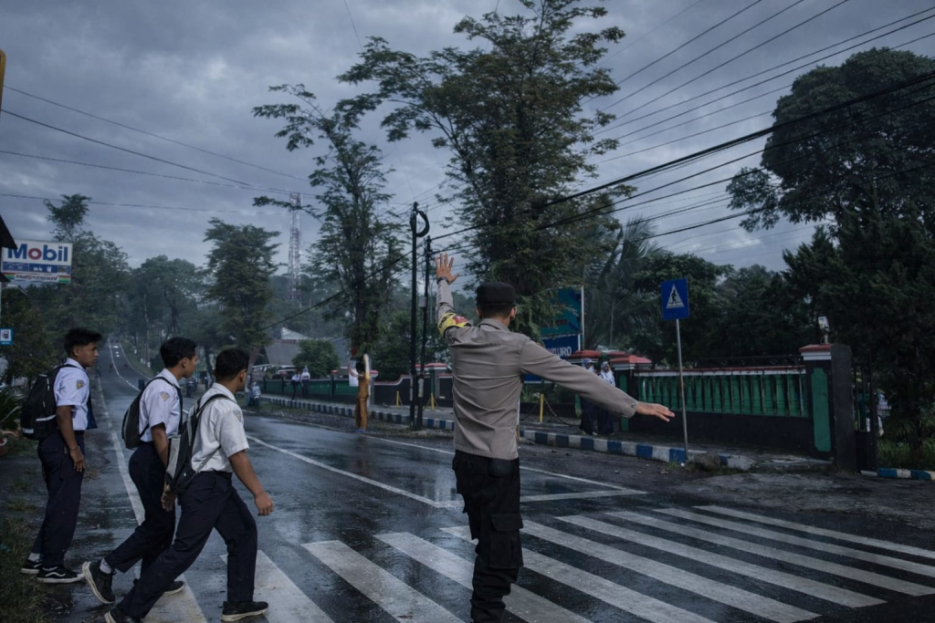 Anggota Polsek Senduro ketika menyebrangkan siswa sekolah