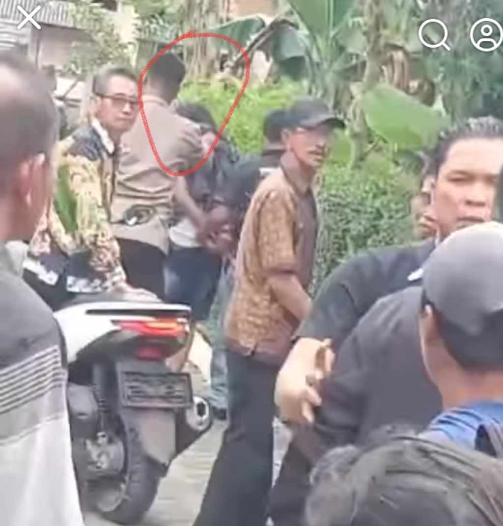 Terduga pelaku saat dibawah oleh petugas kepolisian (lingkaran merah)