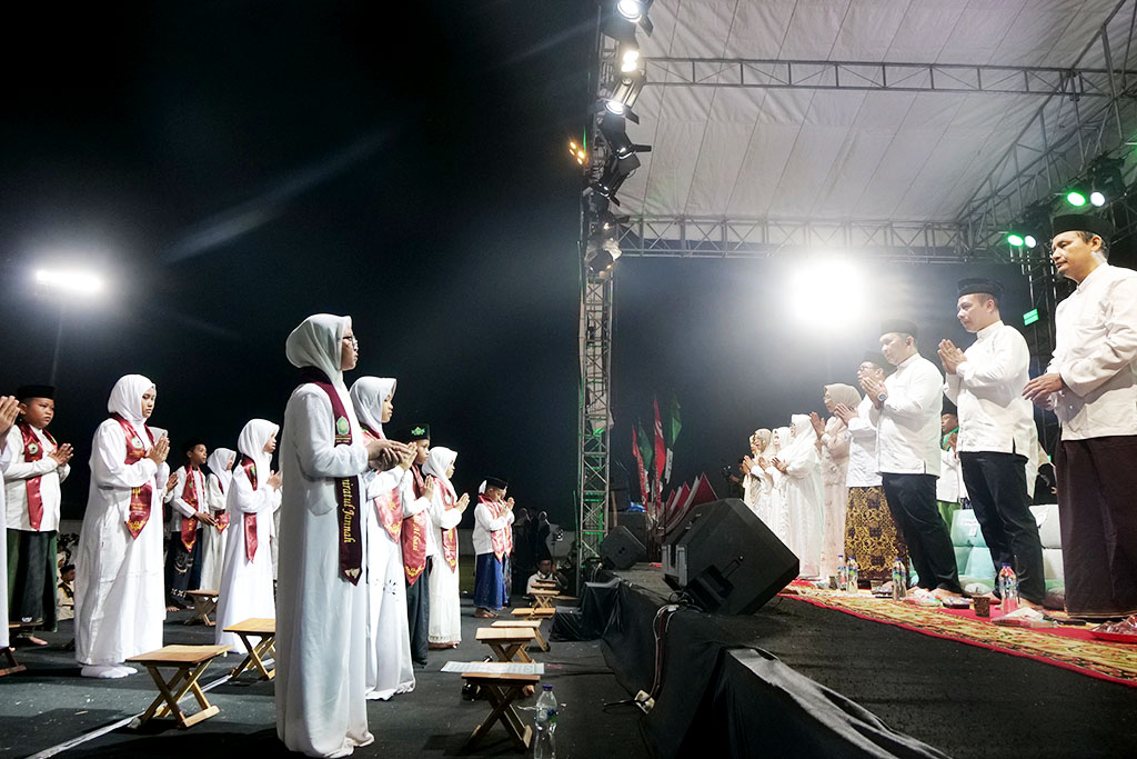 Ribuan santri berdiri khidmat di bawah cahaya panggung, melantunkan ayat suci dalam Wisuda Akbar Tartil dan Tahfidz di Stadion Semeru, Lumajang
