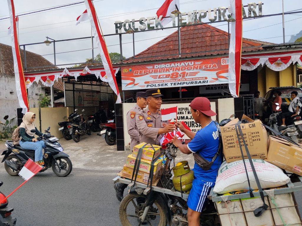 Kapolsek Tempursari membagikan bendera merah-putih kepada pengendara